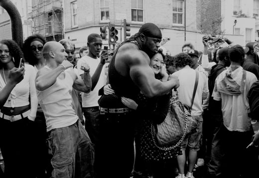 A black and white photo of a crowd with two people hugging in the middle